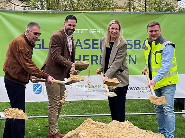 Projektbeteiligte mit Spaten in der Hand vor einem Sandhaufen