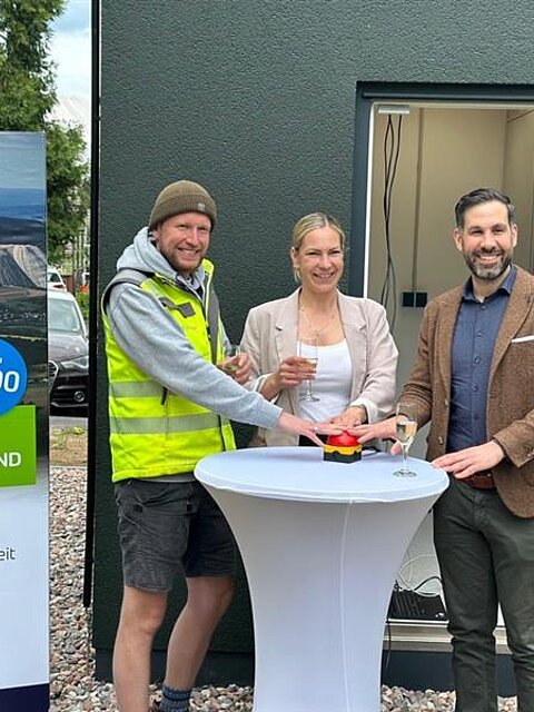 Projektverantwortliche stehen vor dem PoP Gebäude und drücken gemeinsam einen großen Knopf