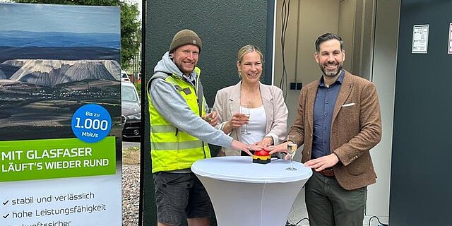 Projektverantwortliche stehen vor dem PoP Gebäude und drücken gemeinsam einen großen Knopf