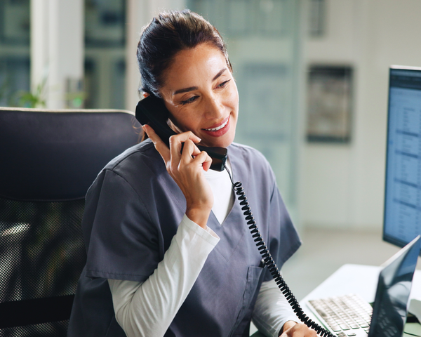 Rufnummernmitnahme für Geschäftskunden Mitarbeiterin telefoniert am Arbeitsplatz mit fester Rufnummer im Unternehmen