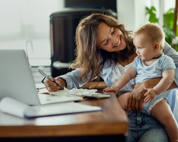 Mutter arbeitet mit Baby auf dem Schoß am Laptop – modernes Familienleben mit Glasfaser