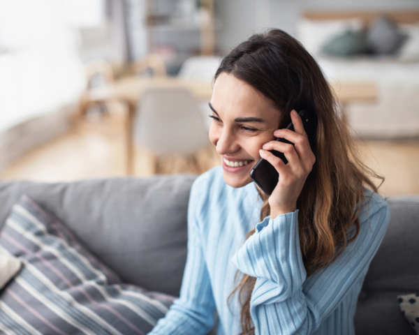 Frau sitzt auf dem Sofa und telefoniert