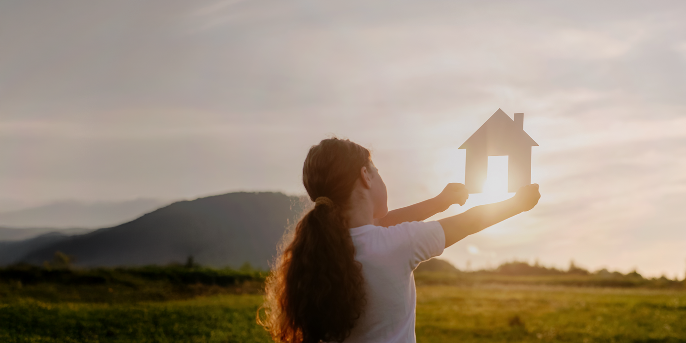 Ein Kind hält ein Haus in die untergehende Sonne – ein Symbol für Zukunft, Neubeginn und nachhaltiges Bauen. Das Bild steht für den Wunsch nach einem vernetzten, modernen Zuhause von Anfang an – mit zukunftssicherem Glasfaseranschluss.
