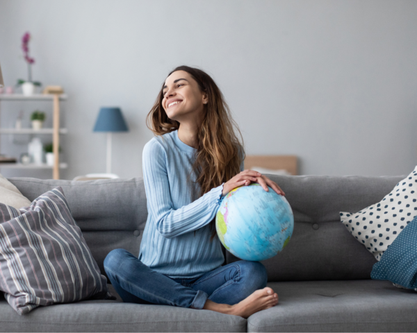 Frau sitzt auf dem Sofa mit Globus auf dem Schoß